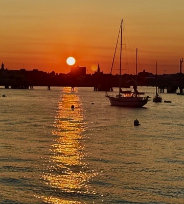 Sunset light tracing a glitter path across harbor water